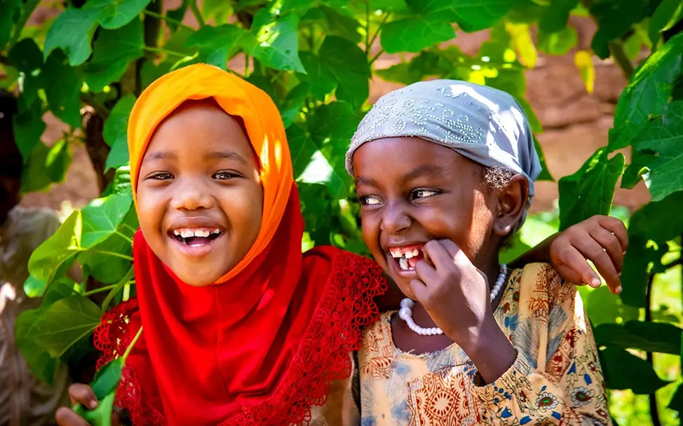 Kinderrechte leicht erklärt: Zwei Mädchen lachen Arm in Arm.