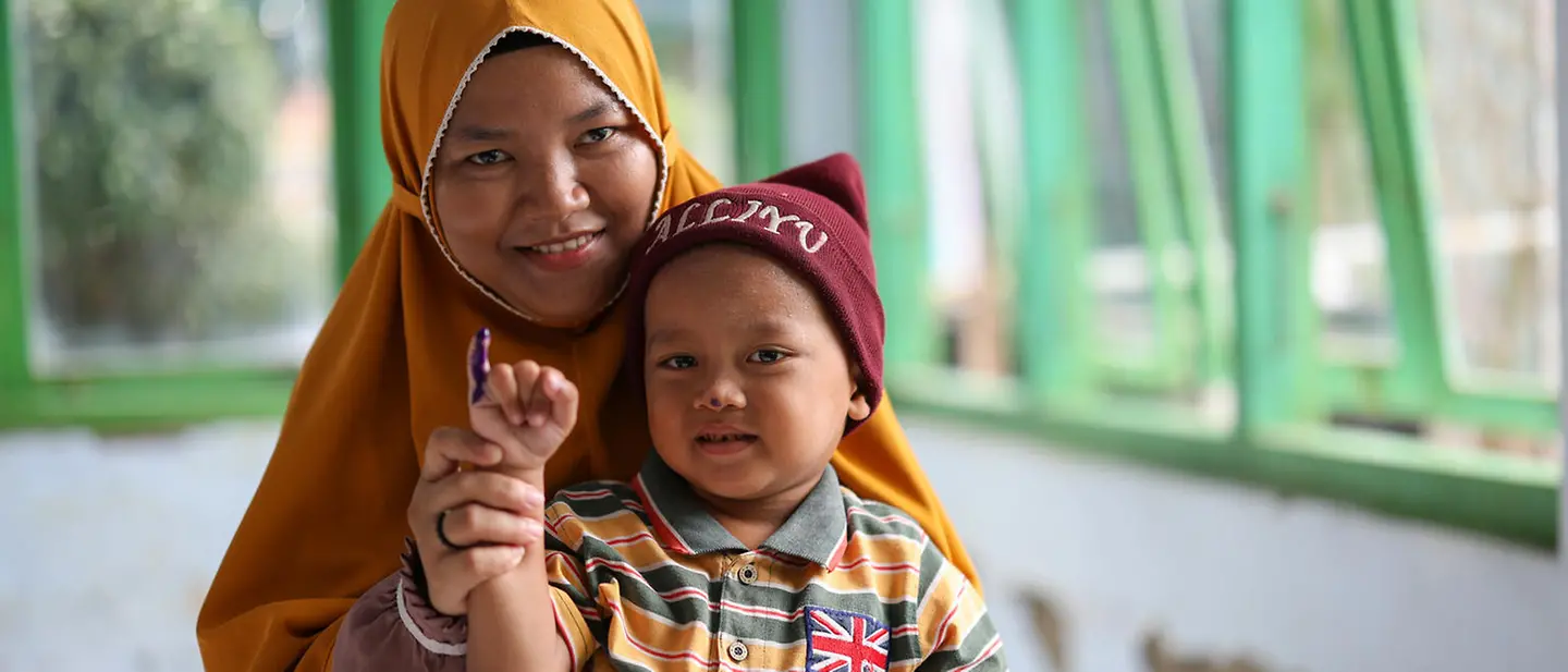 Indonesien spenden: Ein Kleinkind auf dem Schoß seiner Mutter wurde eben gegen Polio geimpft. 