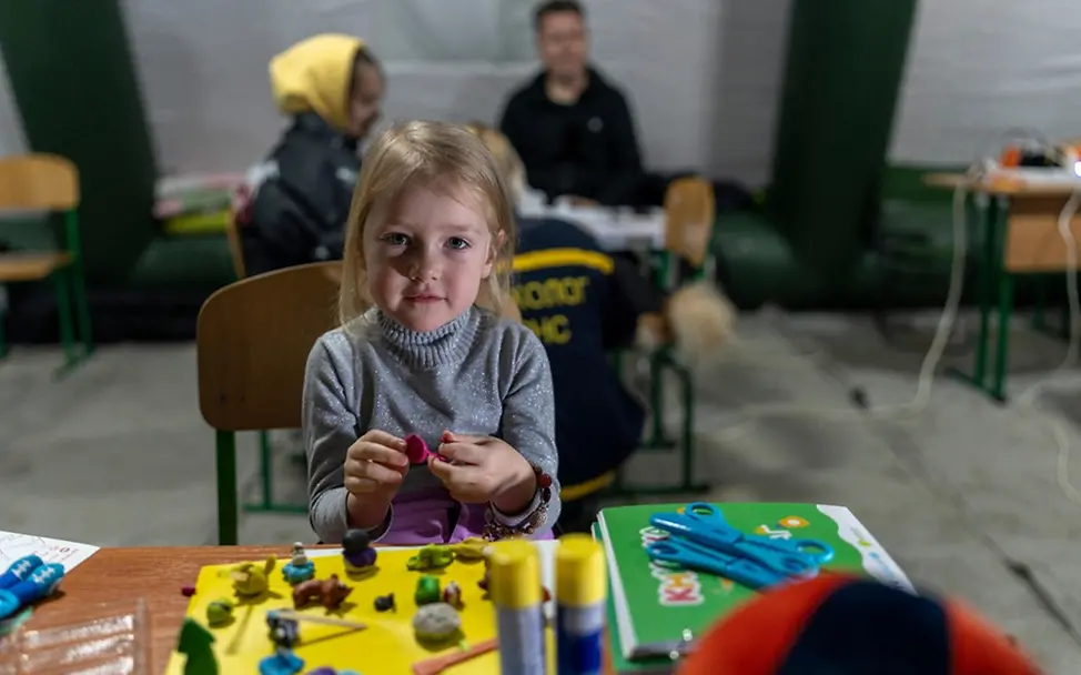 Arina (3) spielt mit Knete und wärmt sich in einem beheizten mobilen Zelt auf.