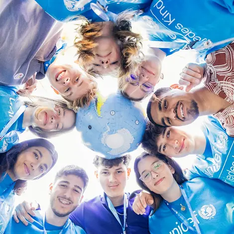 Teilnehmer und Globus in einem Teamkreis beim JugendFestival 2024. | © UNICEF/UNI595608/Stroisch Teilnehmer und Globus in einem Teamkreis beim JugendFestival 2024.