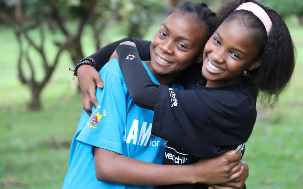 Was ist Rassismus: UNICEF setzt sich weltweit für Kinderrechte und gegen Ungerechtigkeit ein. Rassismus einfach erklärt: Zwei Mädchen umarmen sich lachend.