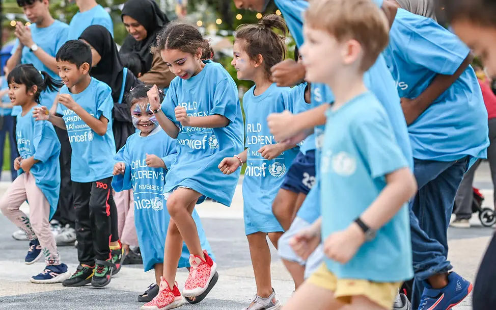 Was ist Rassismus: Alle Menschen sollen die gleichen Chancen haben. Rassismus einfach erklärt: Kinder und Erwachsene in UNICEF-Shirts tanzen