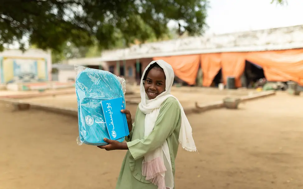 UNICEF Impact Circle: Ein Mädchen im Sudan erhält einen Schulrucksack. 