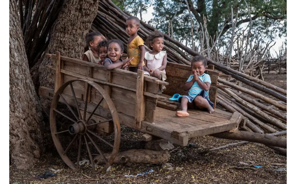 Kinder sitzen auf einem Kutschwagen.