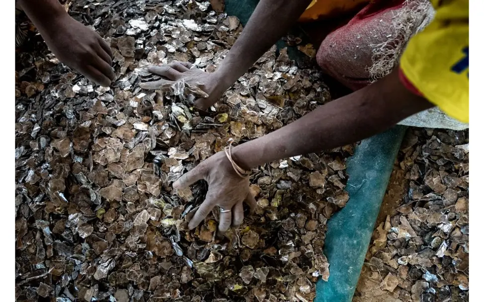 Hände wühlen in Mica-Scherben.