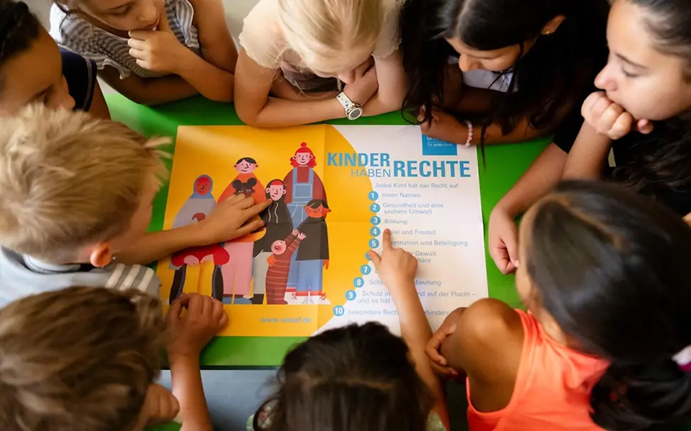 Kinderrechteschulen: Kinder einer UNICEF-Kinderrechteschule schauen ein Kinderrechteplakat an.