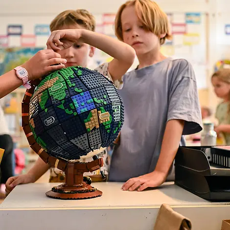 Klimaschutz kindgerecht erklärt: Wir alle können etwas für den Klimaschutz tun. | © UNICEF/Paula G. Vidal Klimaschutz einfach erklärt: Kinder schauen sich eine Weltkugel aus Legosteinen an.