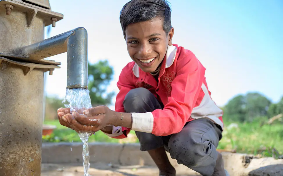 Sauberes Wasser: Ein Junge in Indien trinkt Wasser aus einer Leitung.