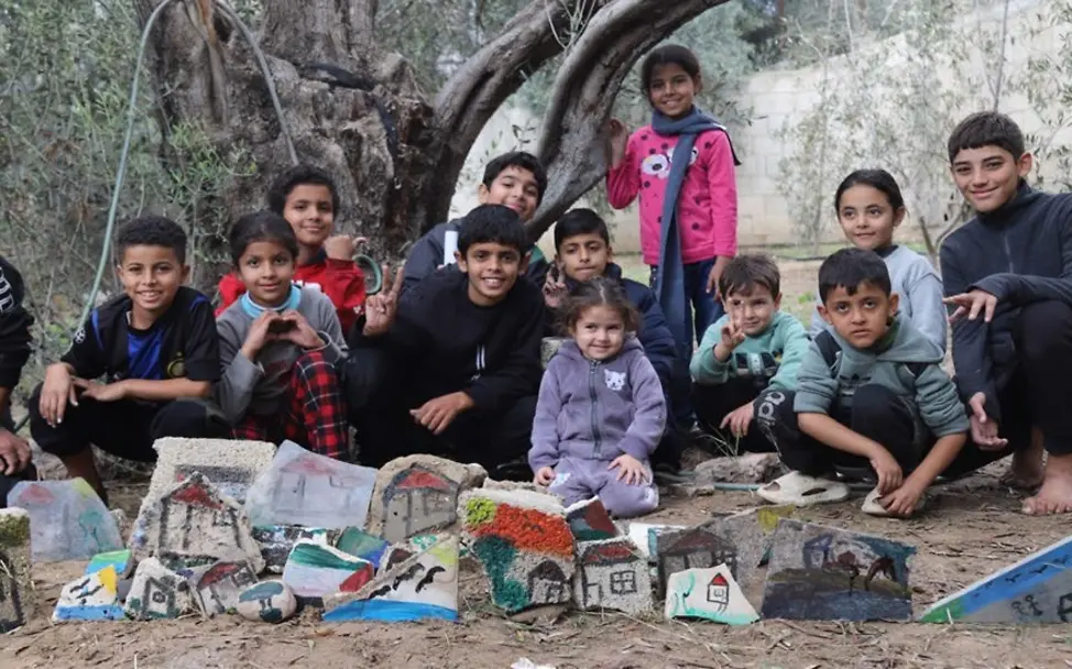 Kinder knien vor ihren Kunstwerken 