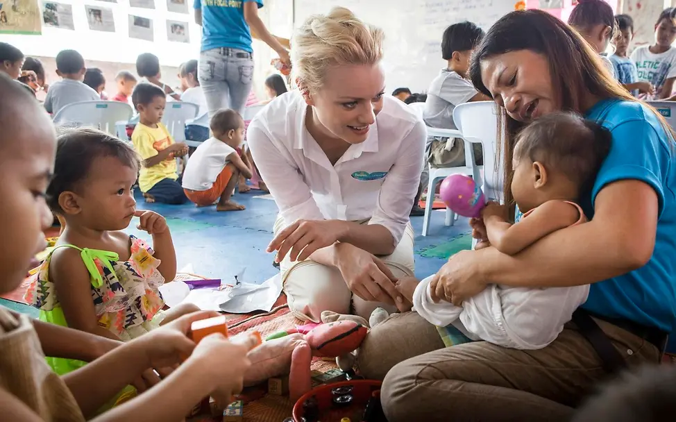 Franziska Knuppe auf den Philippinen © UNICEF/UNI266758/Berger Zwei Personen beschäftigen sich mit Kindern