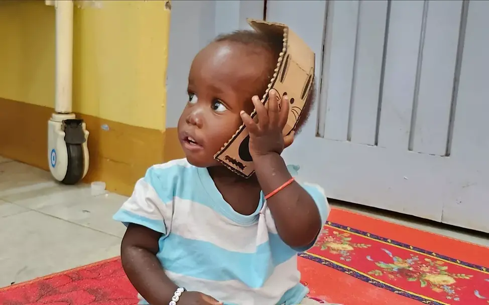 Project Play: Ein Kleinkind spielt mit einem Pappspielzeug