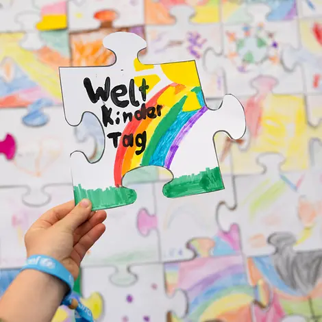 Weltkindertag Kindern erklären: Am Weltkindertag stehen die Kinderrechte im Mittelpunkt. | © UNICEF/Etges Weltkindertag einfach erklärt: Eine Kinderhand hält ein gemaltes Puzzleteil.