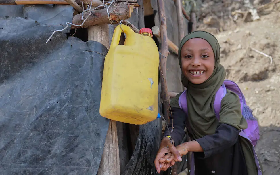 Wasserknappheit weltweit: Ein Mädchen wäscht die Hände an einem Wasserkanister vor einer Latrine.