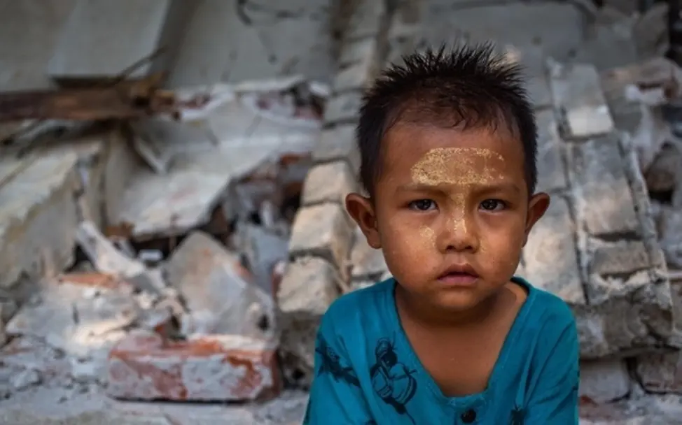 Kind in Mandalay sitzt vor den Trümmern eines zerstörten Gebäudes nach dem Beben