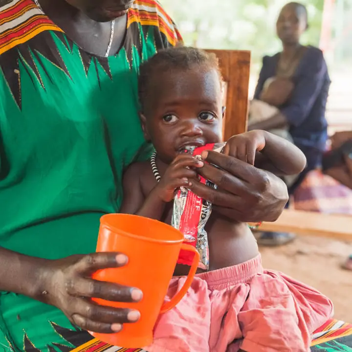 Hunger in Kenia: Ein Kleinkind auf dem Schoß seiner Mutter wird mit Erdnusspaste gefüttert. 