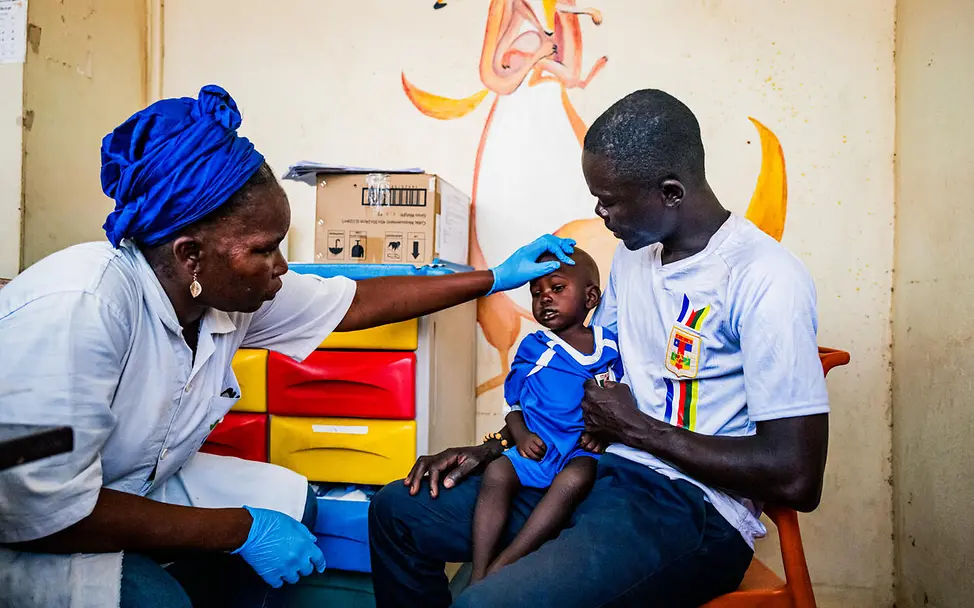 Hunger in der Zentralafrikanischen Republik: Ein Kleinkind auf dem Schoß seines Vaters wird im Krankenhaus untersucht.