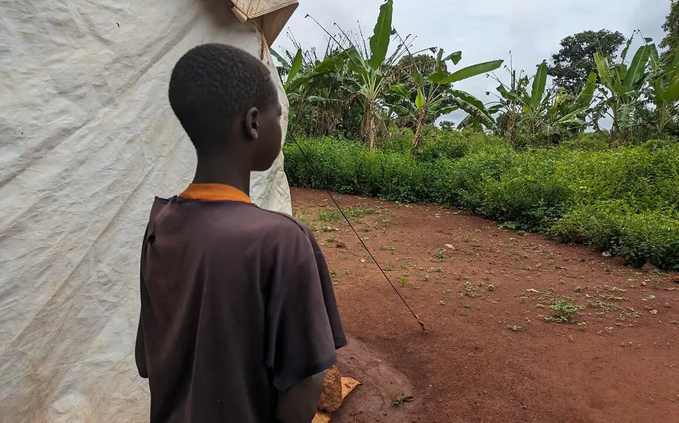 Hunger in der Zentralafrikanischen Republik: Rückenansicht eines Jungen, der neben einem Zelt steht. 