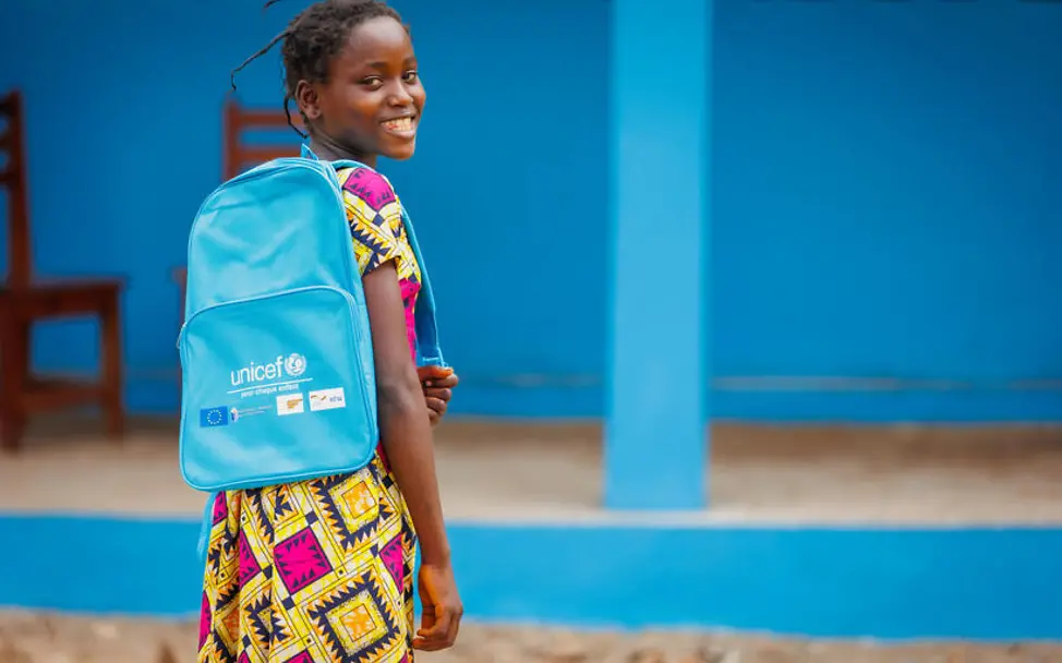 Hunger in der Zentralafrikanischen Republik: Ein Mädchen mit UNICEF-Schulrucksack blickt lachend über die Schulter. 