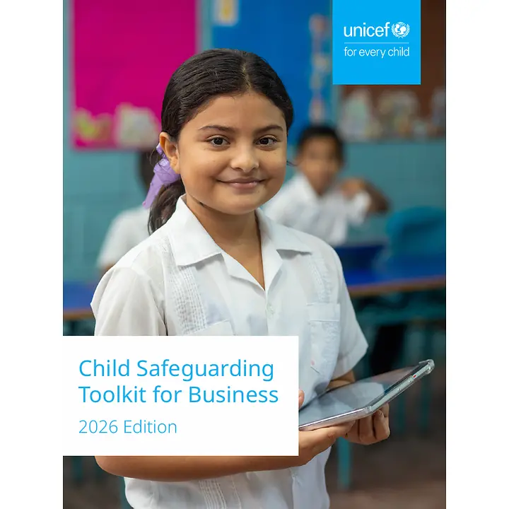 Ein Mädchen steht mit einem Tablet in der Hand im Klassenzimmer.