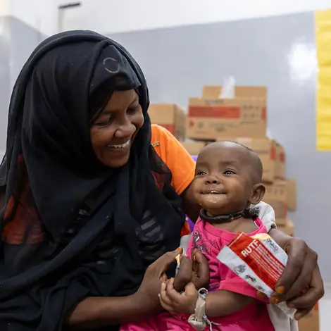 Mutter füttert Kind auf ihrem Schoß