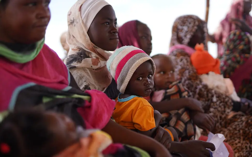 Eine Gruppe Kinder und Frauen sitzen und warten