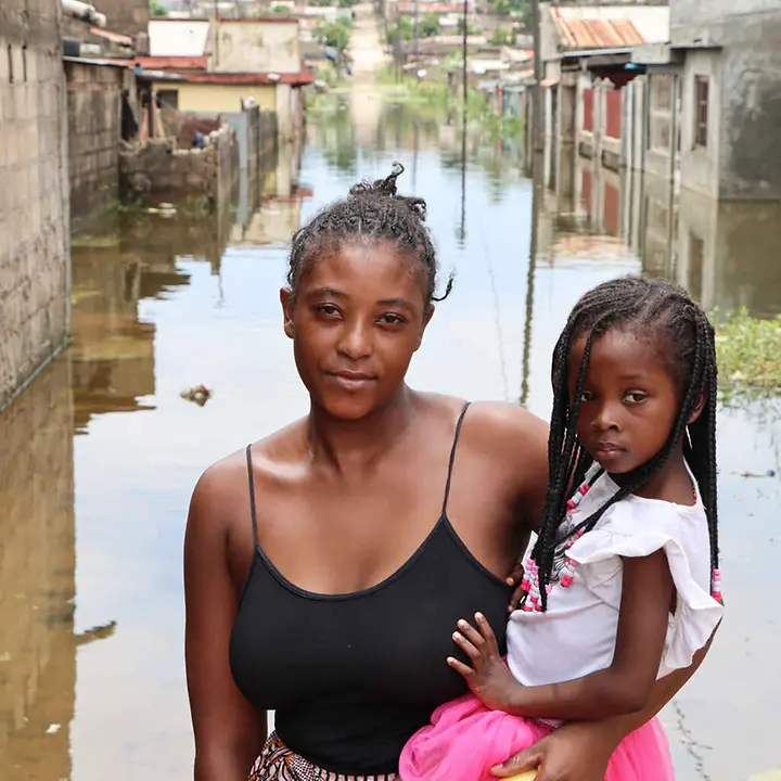 Mosambik Überschwemmungen: Eine Mutter mit Kind steht vor einer überschwemmten Straße.