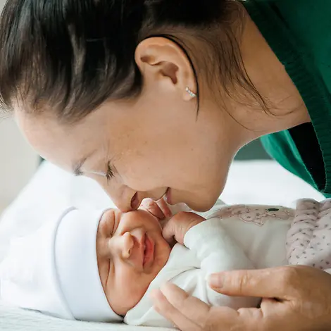 Impfungen Baby: Eine Mutter kuschelt mit ihrem Baby. 