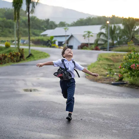 Recht auf gewaltfreie Erziehung: Ein Junge läuft lachend mit ausgebreiteten Armen.