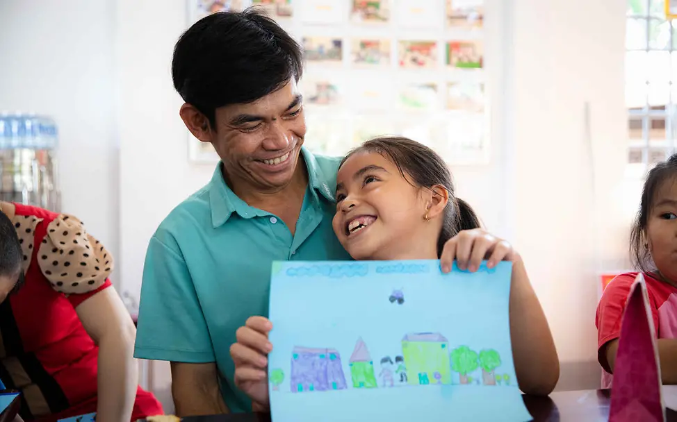 Recht auf gewaltfreie Erziehung: Ein Vater lächelt seine Tochter auf seinem Schoß an. 
