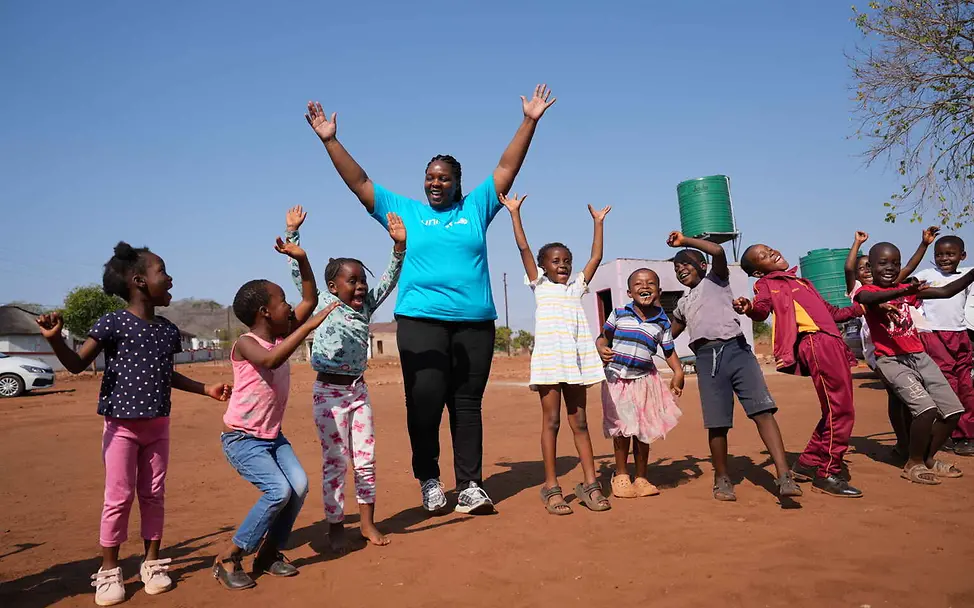 Recht auf gewaltfreie Erziehung: Kinder spielen und lachen mit einer UNICEF-Helferin.