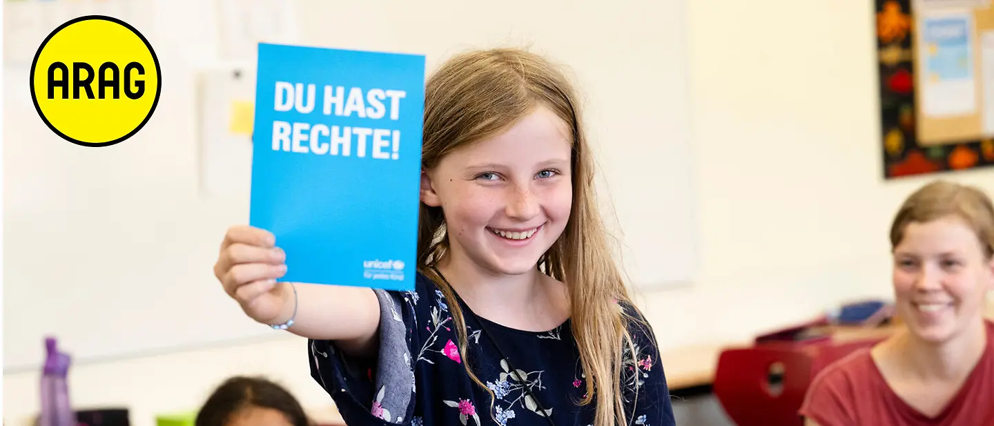 Ein Kind hält ein "Du hast Rechte" Büchlein hoch | © UNICEF Ein Kind hält ein "Du hast Rechte" Büchlein hoch