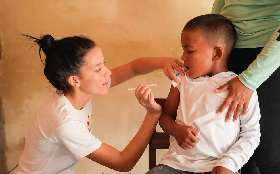 Warum impfen: Eine Gesundheitshelferin impft einen Jungen in den Arm.