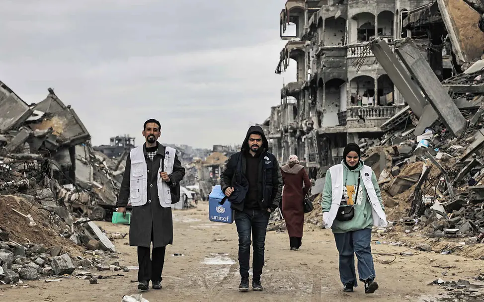 Warum impfen: UNICEF-Gesundheitshelfer*innen laufen durch eine zerstörte Straße in Gaza.