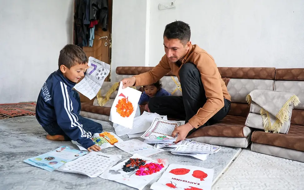 Kindererziehung Tipps: Rohat (6) und sein Vater Ferhat schauen sich gemeinsam Rohats Zeichnungen an.