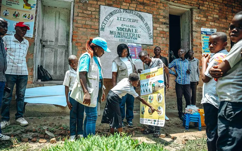 Ebola spenden: Eine UNICEF-Mitarbeiterin zeigt Kindern im Kongo, wie sie sich vor Ebola schützen können. 