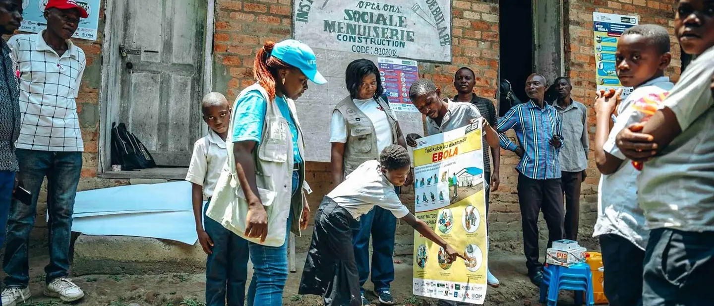 Eine UNICEF-Mitarbeiterin zeigt Kindern ein Poster mit Hygieneschutz-Maßnahmen gegen Ebola. | © UNICEF/Badimu Ebola spenden: Eine UNICEF-Mitarbeiterin zeigt, wie man eine Ansteckung und eine größere Epidemie verhindern kann.
