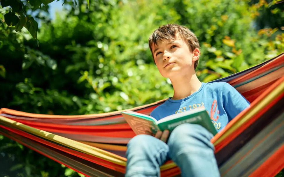 Grundgesetz einfach erklärt: Ein Junge mit einem Buch sitzt in einer Hängematte. 