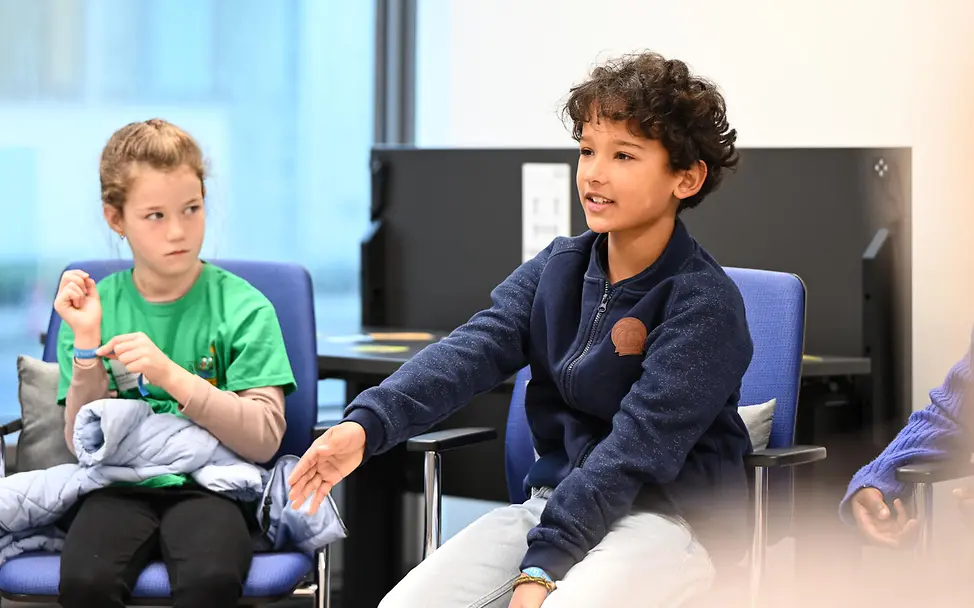 Grundgesetz einfach erklärt: Zwei Kinder sitzen zusammen und sprechen.