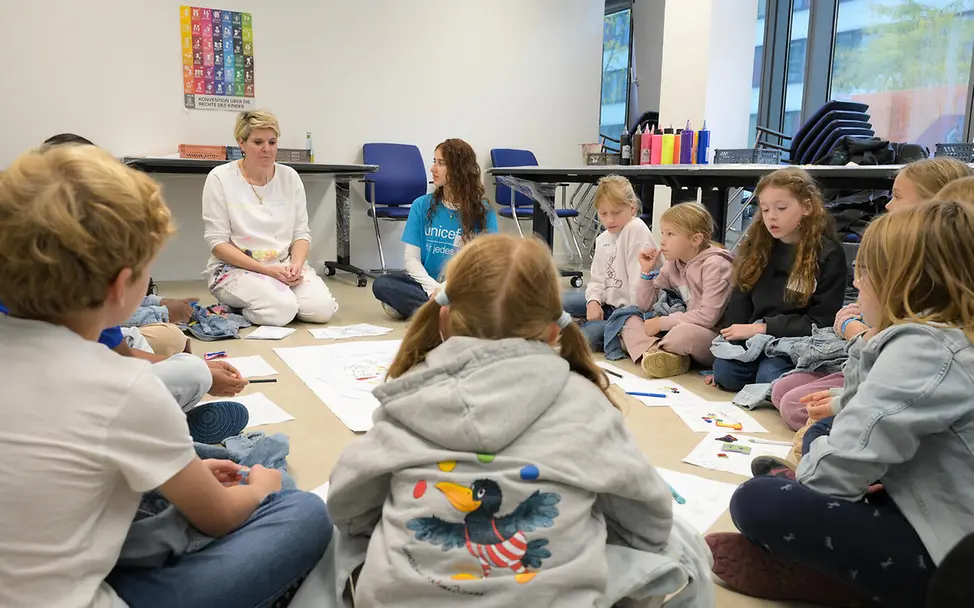 Grundgesetz einfach erklärt: Kinder sitzen in einem Kreis zusammen und sprechen.
