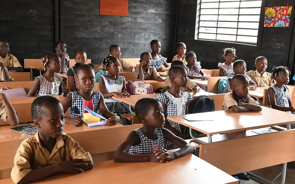 Elfenbeinküste Bildung: Schulkinder sitzen in einem Klassenraum aus recycelten Plastikziegeln.