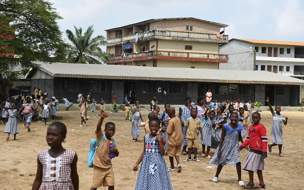 Bildung für die Elfenbeinküste: Schulkinder spielen vor einer Schule aus Recycling-Ziegeln.