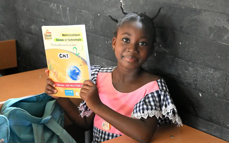 Bildung für die Elfenbeinküste: Ein Schulkind zeigt sein Lernheft in die Kamera. 