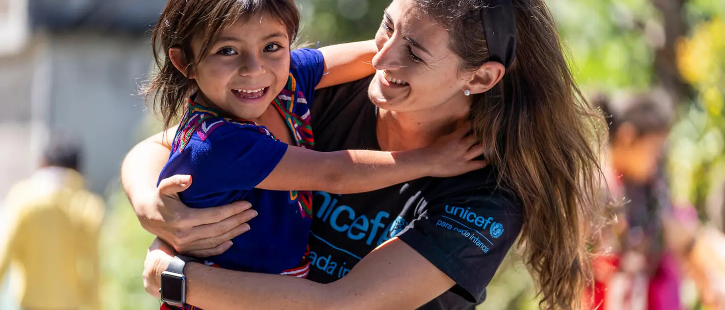 Ein Mädchen in Guatemala umarmt lächelnd eine UNICEF-Mitarbeiterin | © UNICEF/Flores 80 Jahre UNICEF Jubiläum: Das Kinderhilfswerk UNICEF feiert 80-jähriges Bestehen. 80 Jahre Einsatz für Kinder weltweit!