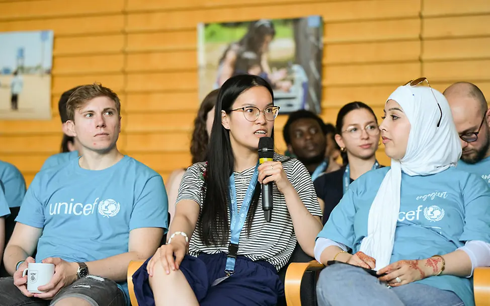 Engagierte der UNICEF-Hochschulgruppe Freiburg spricht beim Jahrestreffen in ein Mikrofon. 