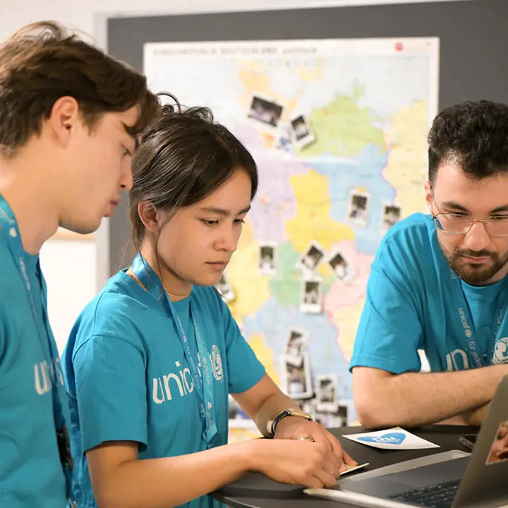 UNICEF-Hochschulgruppe aus Freiburg beim jährlichen Treffen. | © UNICEF/Sachse-Grimm 3 UNICEF-Engagierte stehen an einem Tisch und schauen gemeinsam auf einen Laptop.