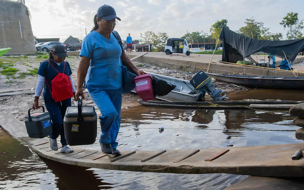 Impfen einfach erklärt: Zwei Gesundheitshelferinnen steigen mit Impfstoffen auf ein Boot.