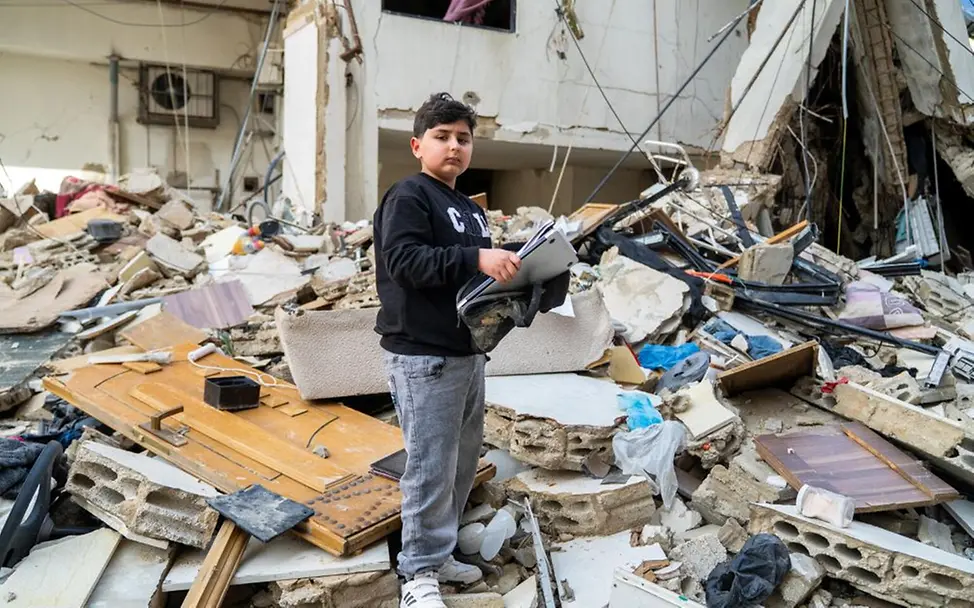 Weltflüchtlingstag 2026: Mahdi (10) steht in den Trümmern des Hauses seines Großvaters. 