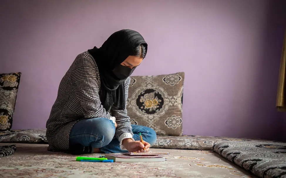 Ohne Schulbildung haben viele Mädchen in Afghanistan keine Chance auf einen Beruf. | © UNICEF/Azizi Bildung in Afghanistan: Ein Mädchen sitzt auf dem Boden und zeichnet.