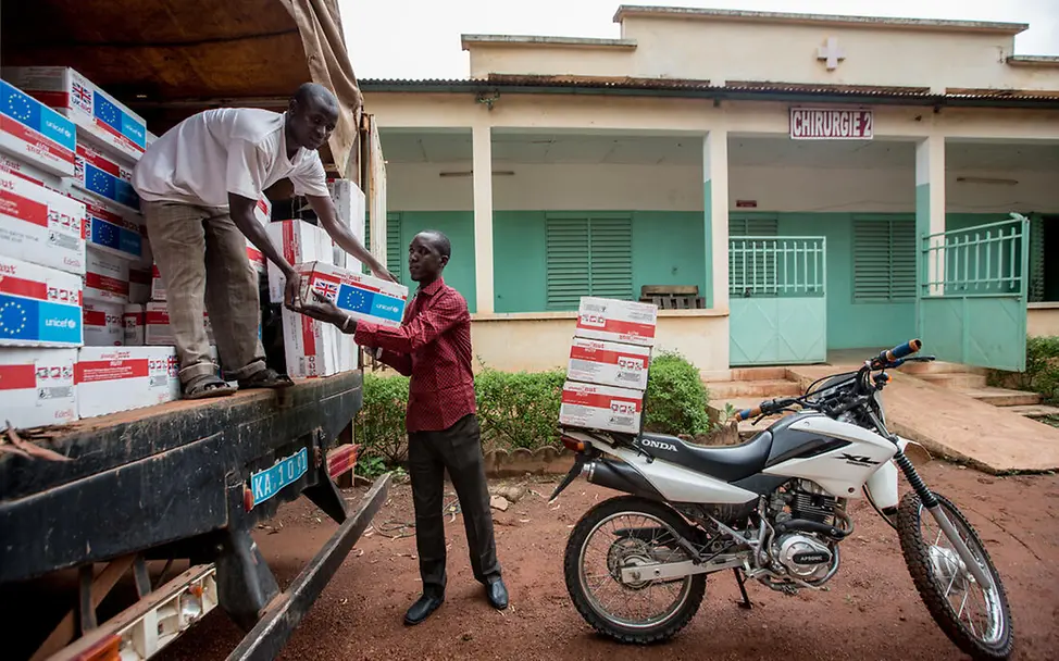 Erdnusspaste spenden: UNICEF-Helfer laden Erdnusspaste von einem Lkw auf ein Motorrad.