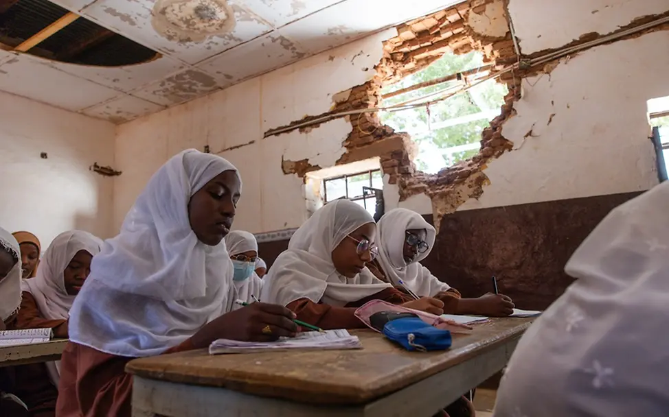 Schwere Kinderrechtsverletzungen: Im Sudan sitzen Mädchen in einer beschädigten Schulen